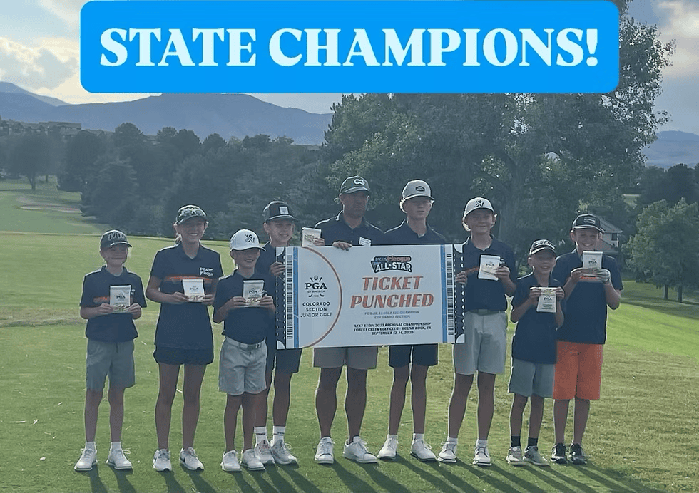 Boys and instructor holding a sign and little pieces of paper in front of them standing on a golf course.