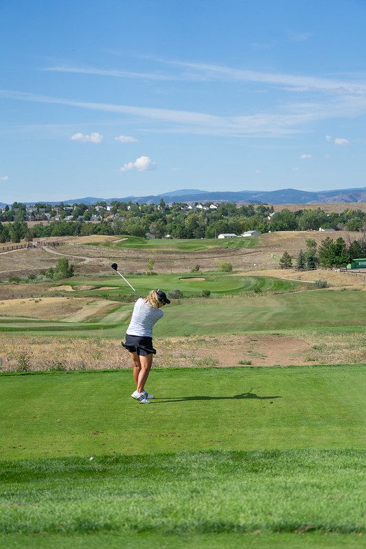 Woman after swinging a golf club on an outdoor course.