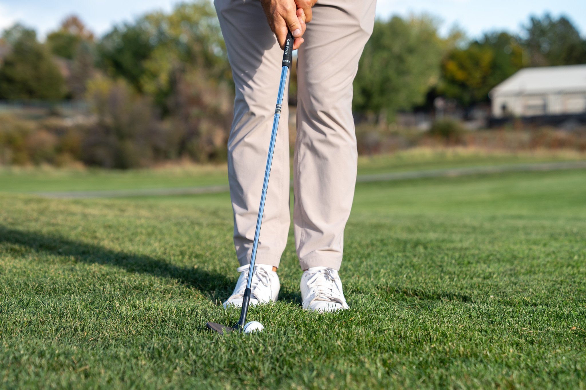 A man standing in front of a golf club touching a ball.
