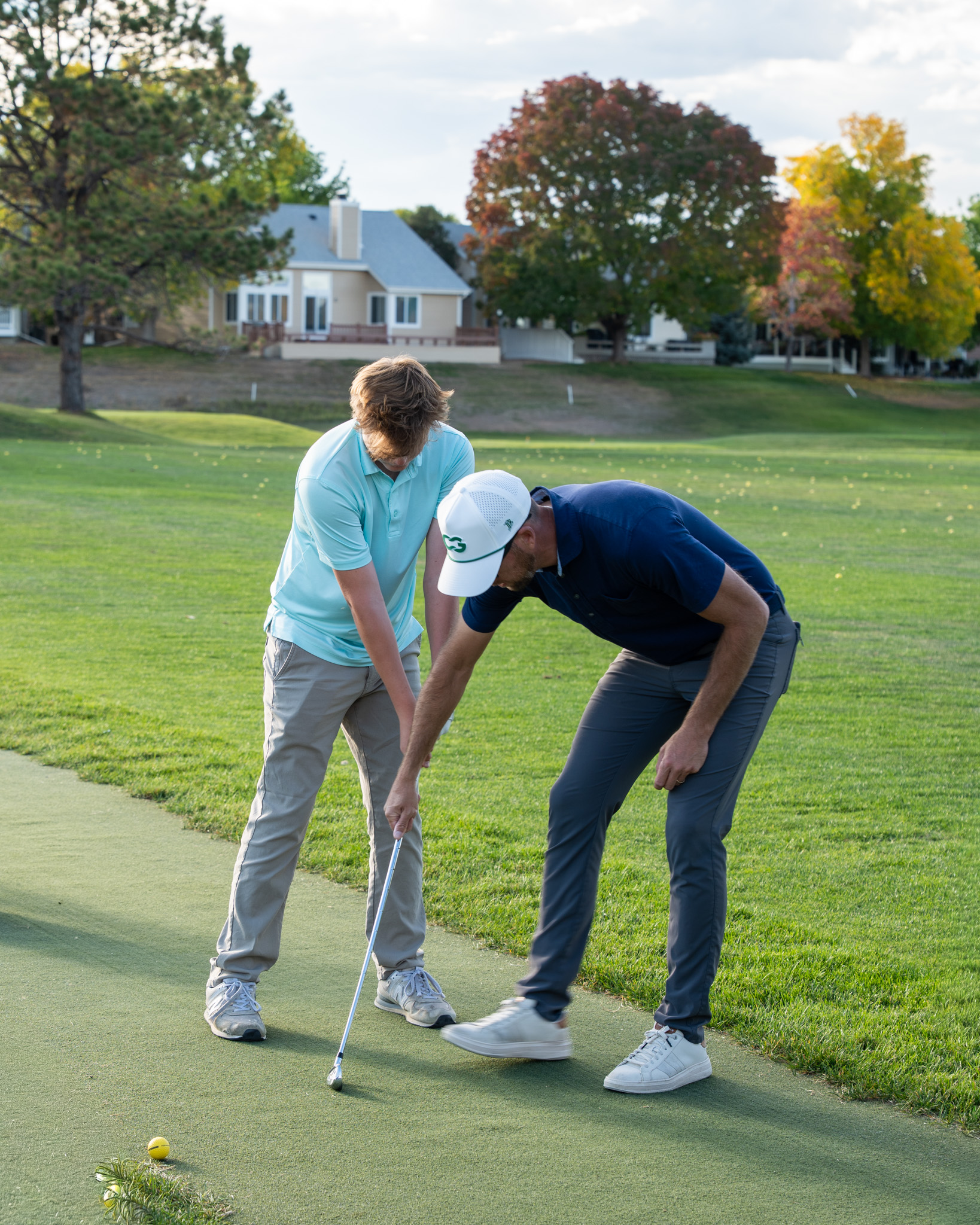 An instructor showing a boy how to swing a golf club.