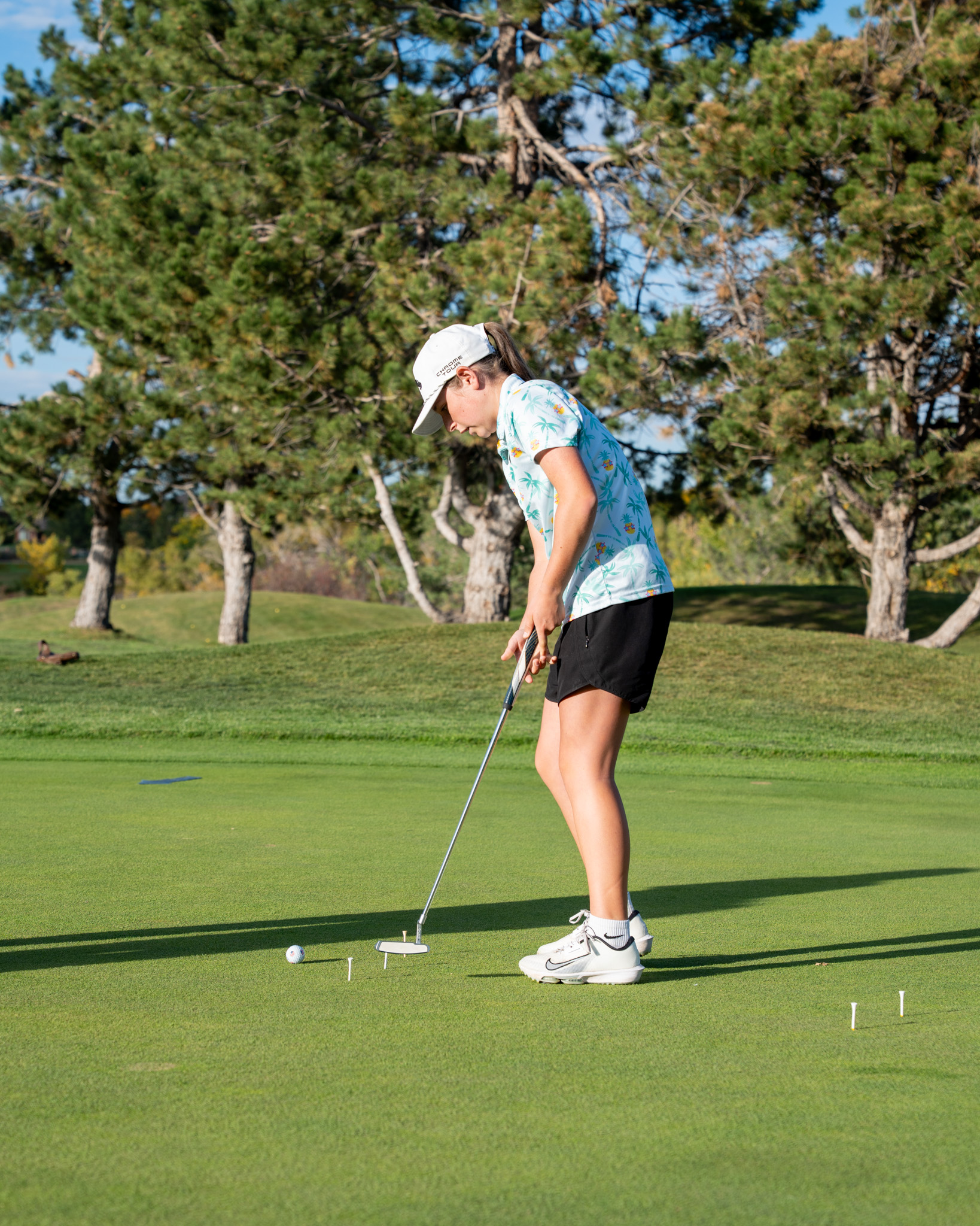 Girl preparing to swing golf club on an outdoor course.