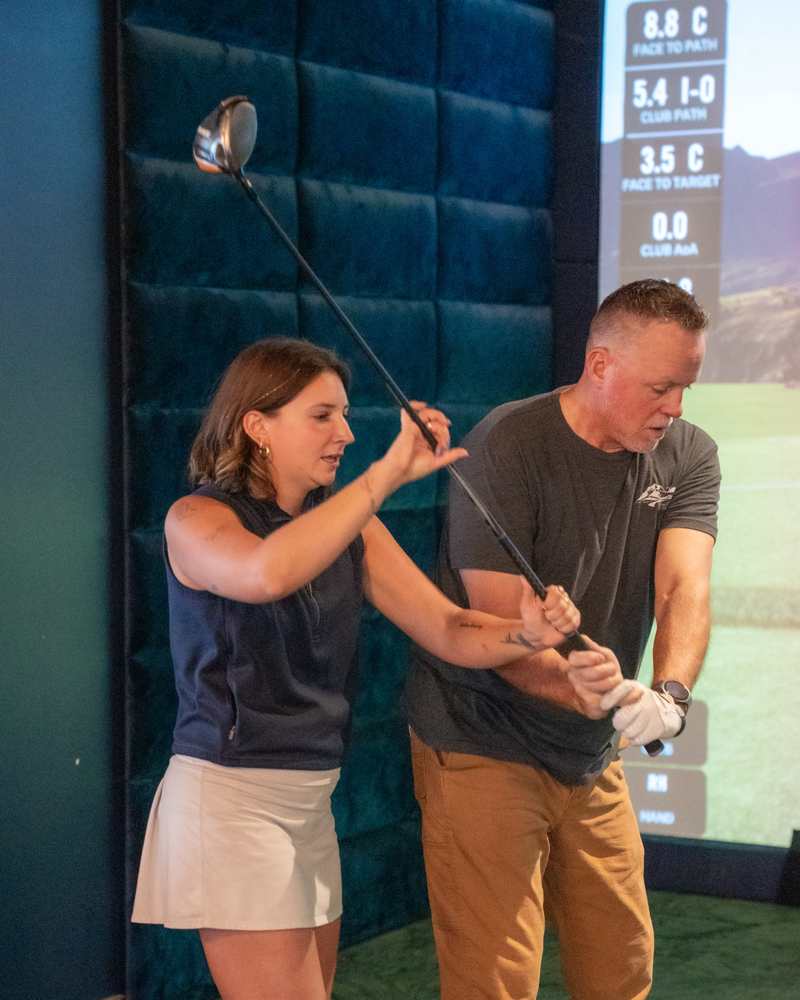 An instructor showing a man how to hold a golf club.
