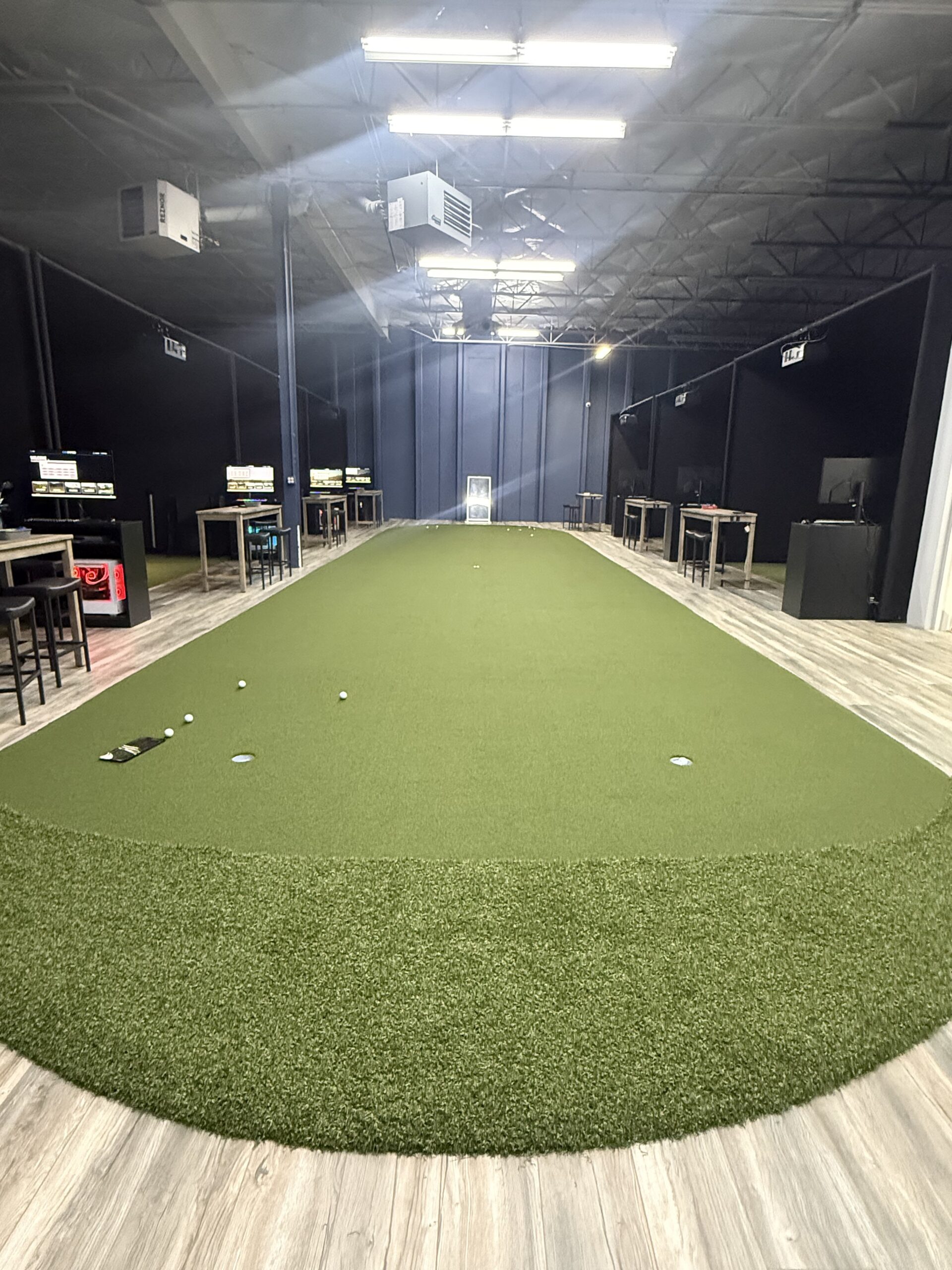 A large indoor putting area in an industrial style facility.