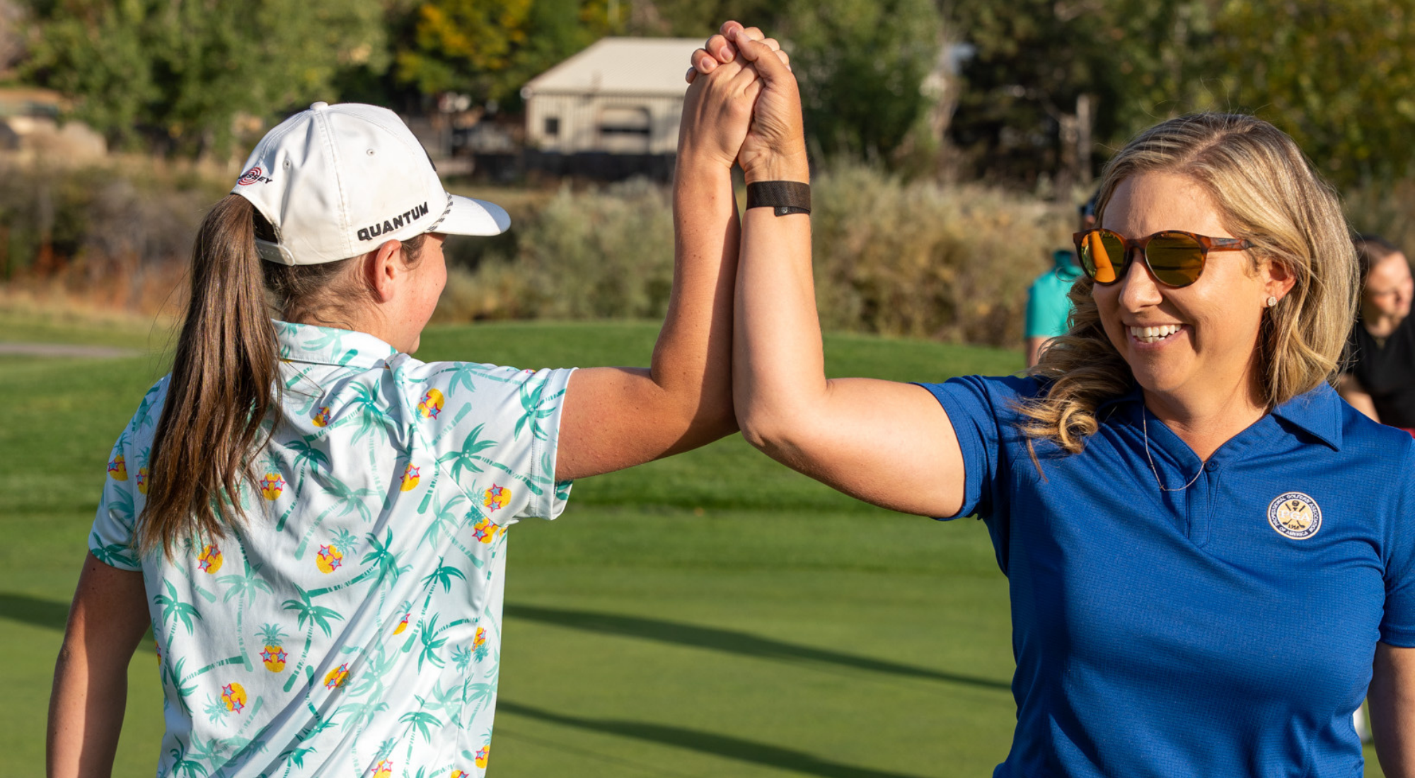 An instructor and girl high fiving and smiling on a golf course.