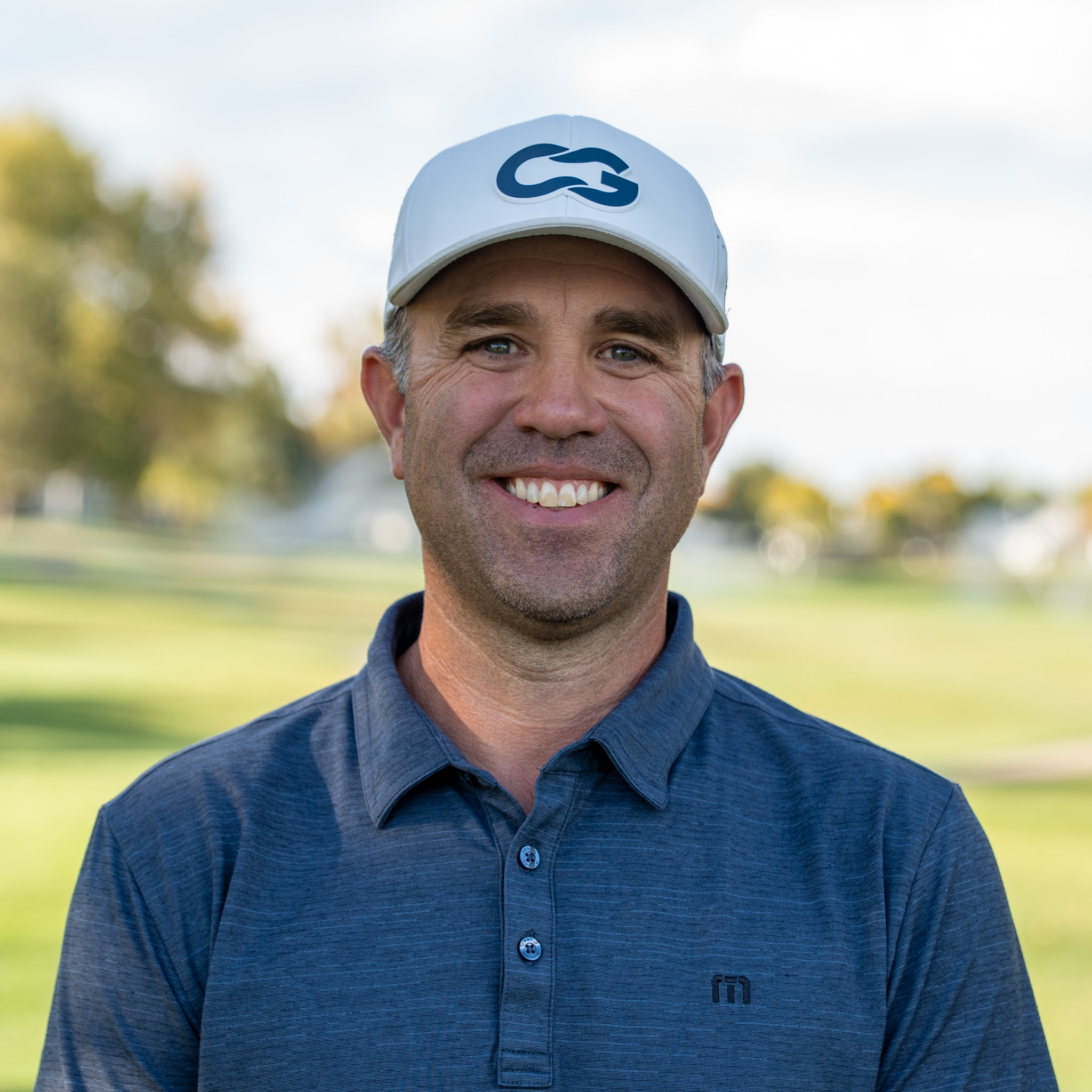 Kyle Voska smiling and looking into the camera on a golf course