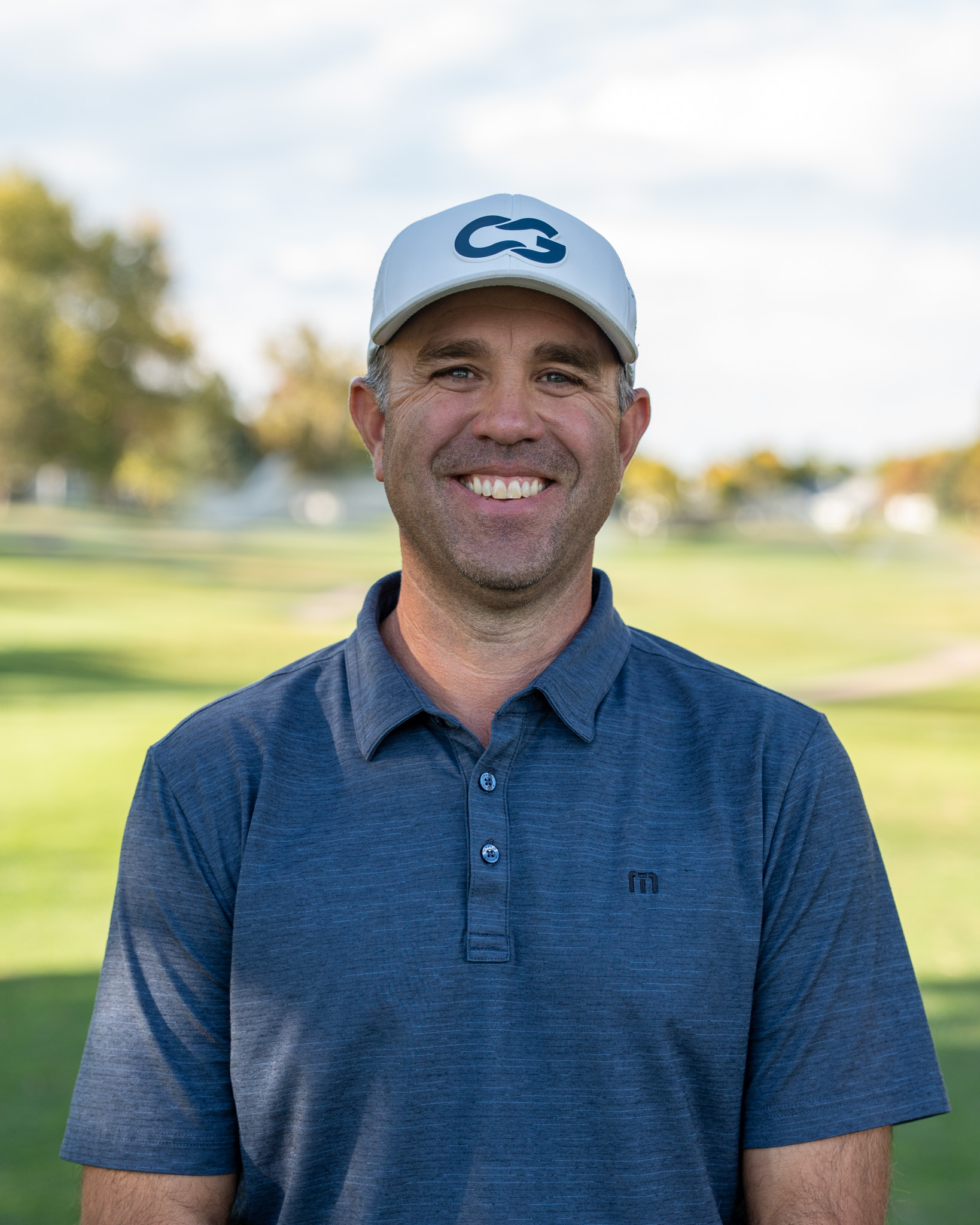 Kyle Voska smiling and looking into the camera on a golf course