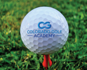 Golf ball sitting on a red tee on green grass with the Colorado Golf Academy logo in the center.