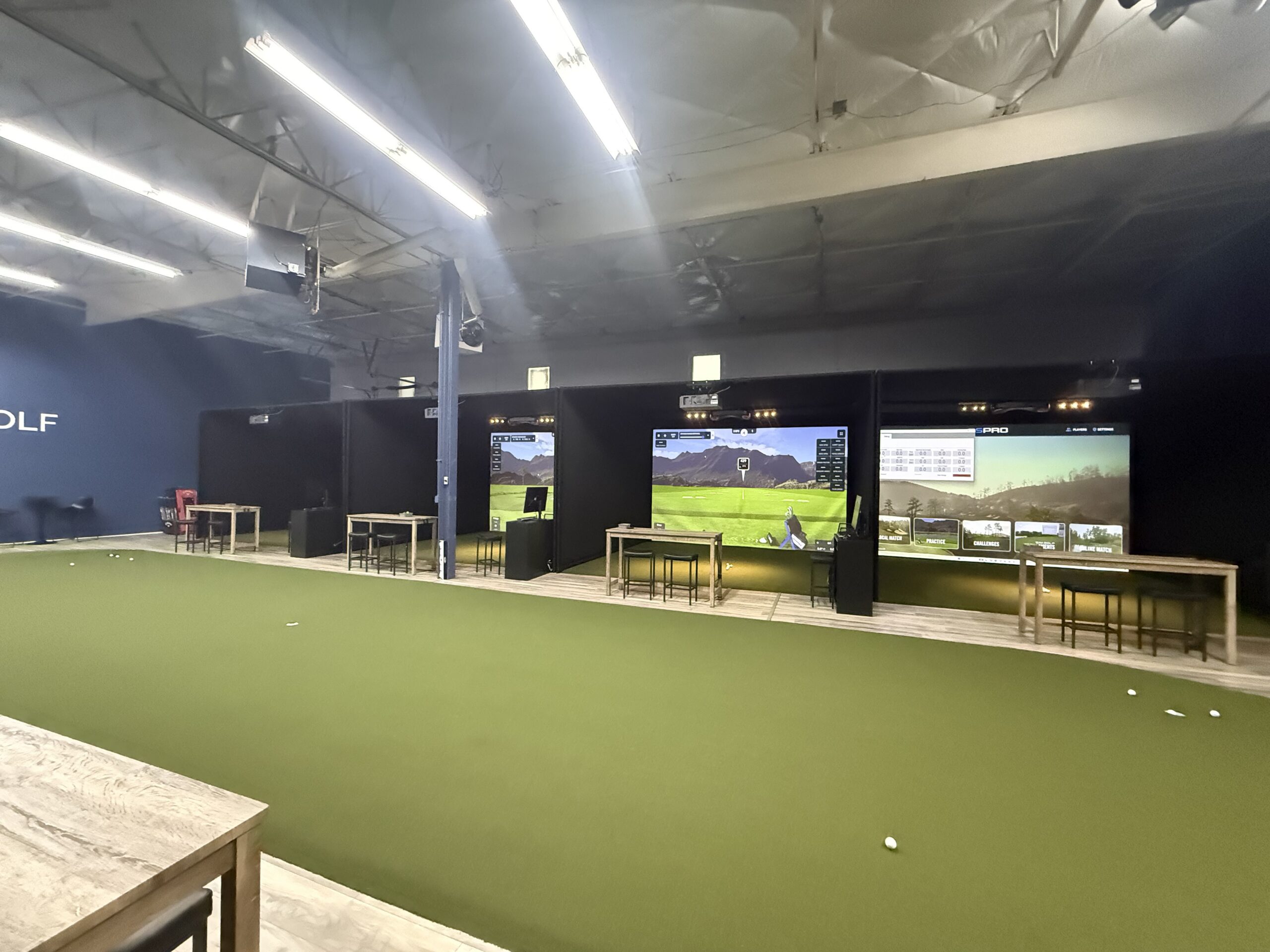Large simulator bays at an indoor golf arena.
