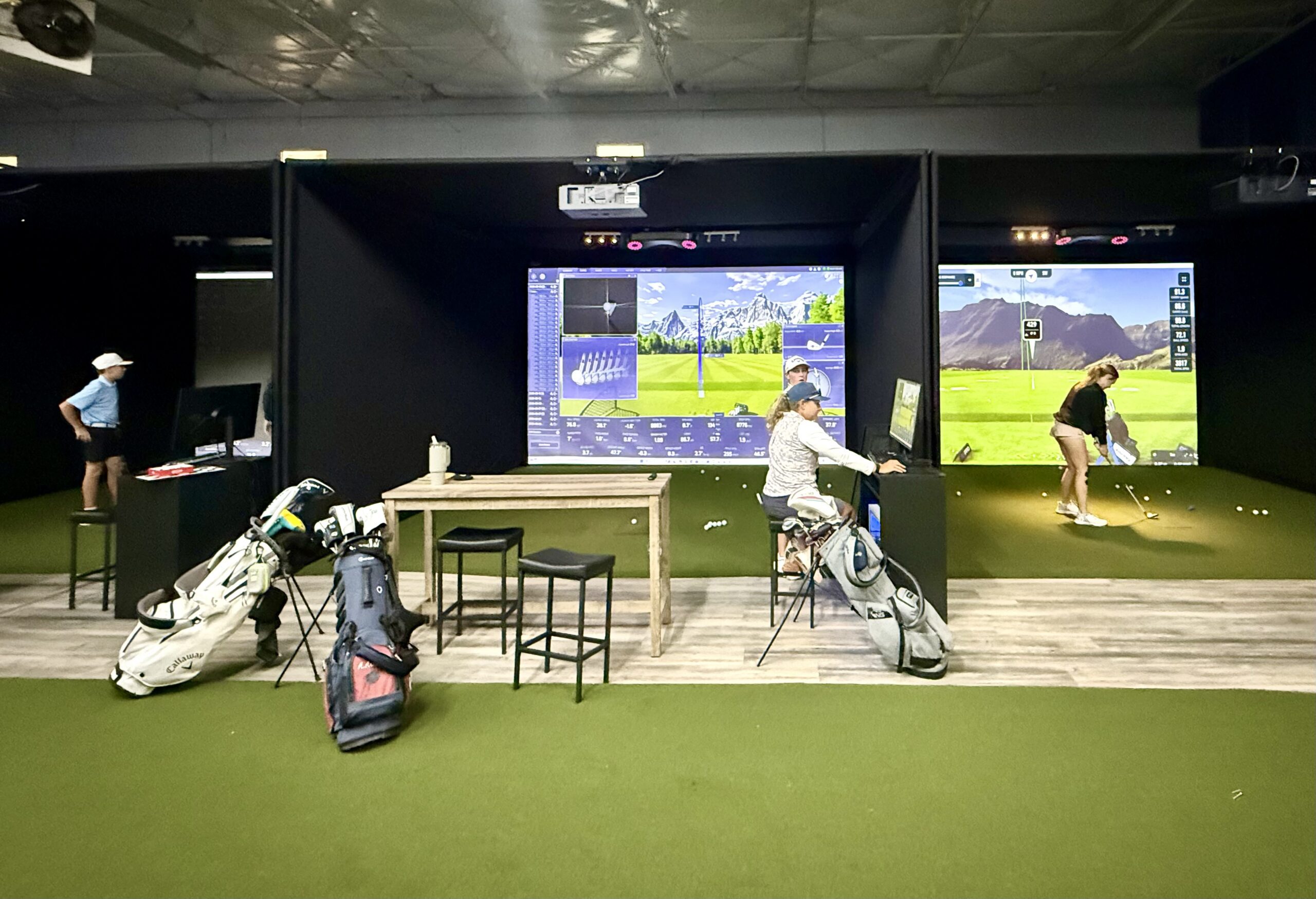 People playing golf at simulator bays.